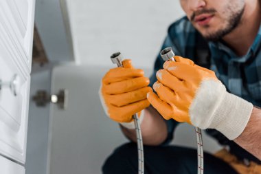 mutfak dolabı yakınında metal hortum tutan handyman seçici odak 