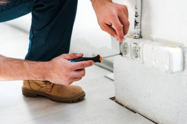 cropped view of repairman sitting while fixing power  clipart