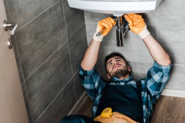 selective focus of repairman fixing water damage with wrench in bathroom  clipart