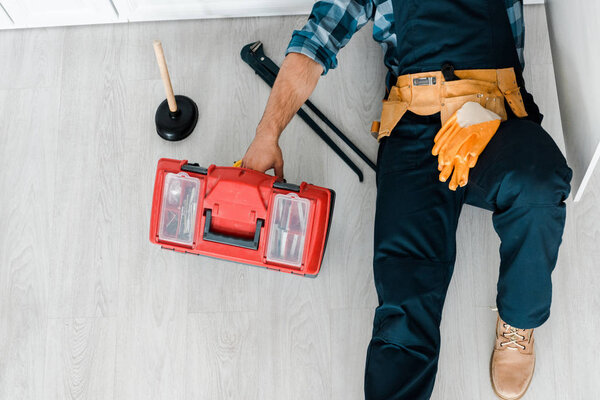 top view of repair lying on floor and working near toolbox 