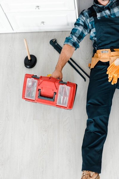 top view of worker lying on floor and working near toolbox 