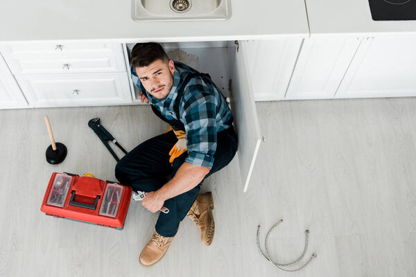 top view of bearded handyman sitting on floor near toolbox 
