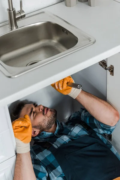 Reparador Guapo Sosteniendo Llave Ajustable Mientras Que Fija Fregadero Cocina — Foto de Stock