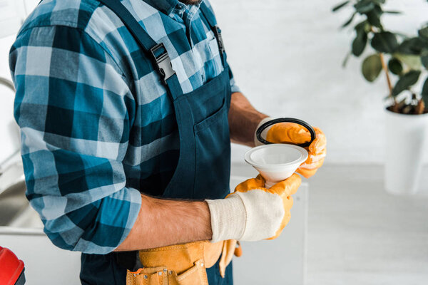 cropped view of repairman holding funnel in kitchen 