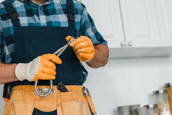 cropped view of repairman in rubber gloves holding metal hose