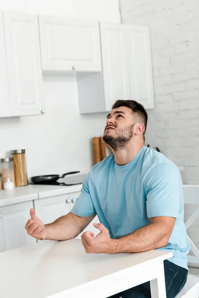 Homem Irritado Gesticulando Enquanto Sentado Perto Mesa Cozinha — Fotografia de Stock
