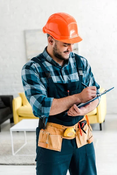 Happy Bearded Worker Safety Helmet Writing While Holding Clipboard — Stock Photo, Image