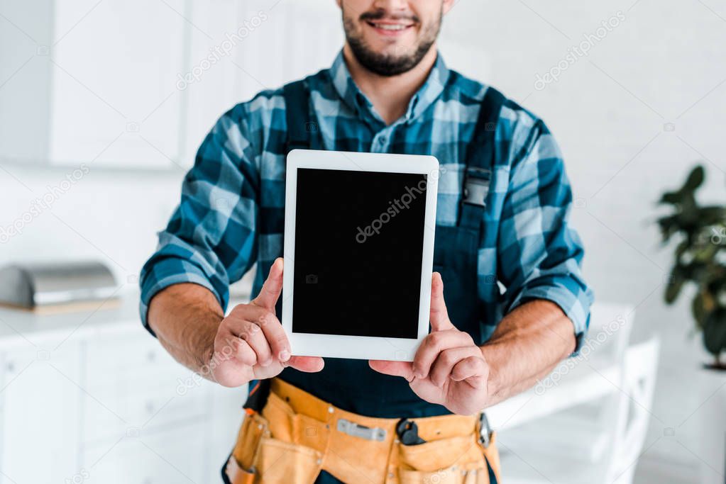 cropped view of happy handyman holding digital tablet with blank screen 