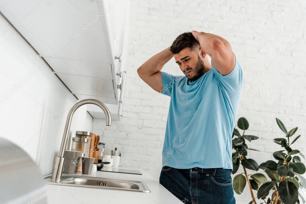 selective focus of upset man looking at sink in modern kitchen 