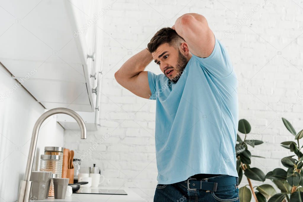 stressed man touching head while looking at sink in modern kitchen 