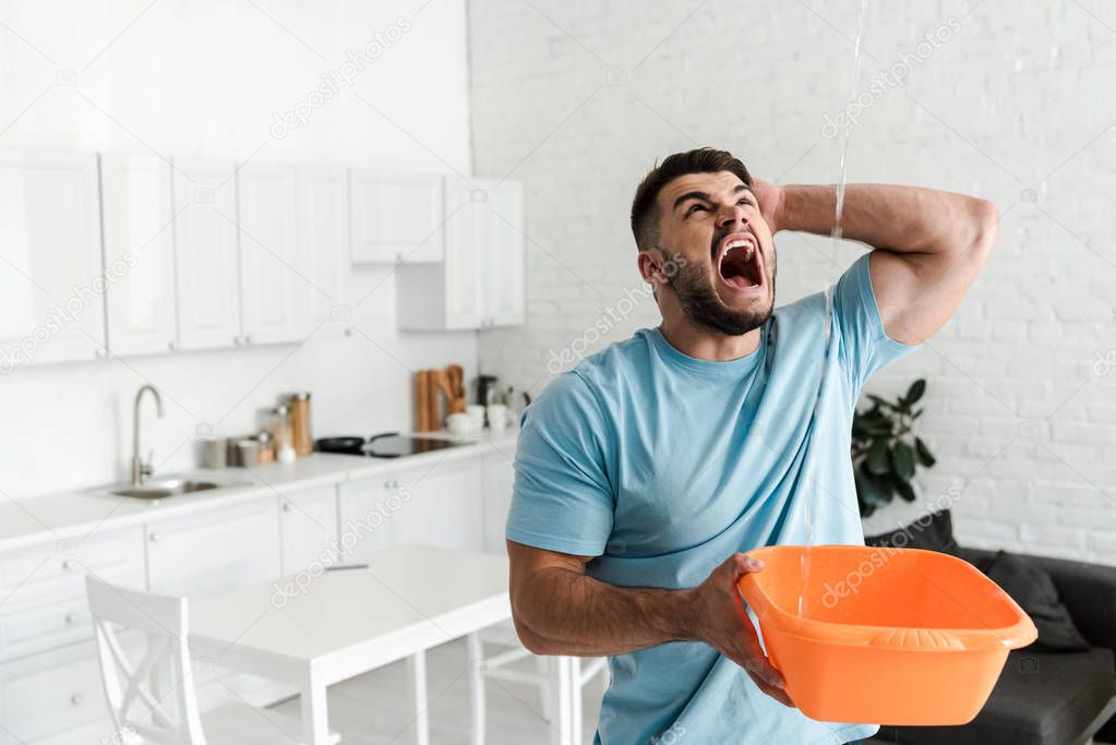 screaming man holding plastic wash bowl near pouring water 