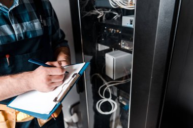 tellerin ve kabloların yakınına yazarken pano tutan işçinin kırpılmış görünümü 