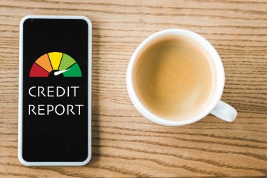 masada kahve fincanı yanında ekranda kredi raporu yazı ile akıllı telefon üst görünümü 