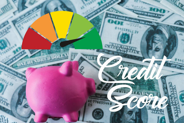 вид розовой копилки рядом с кредитными счетами на банкнотах в долларах
 