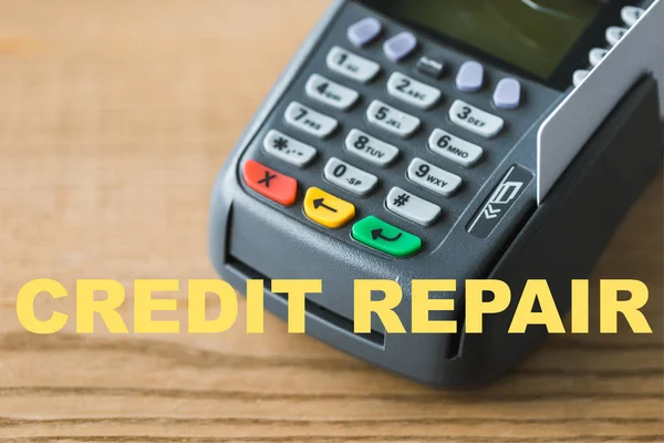 close up of credit card reader near credit repair lettering on wooden table