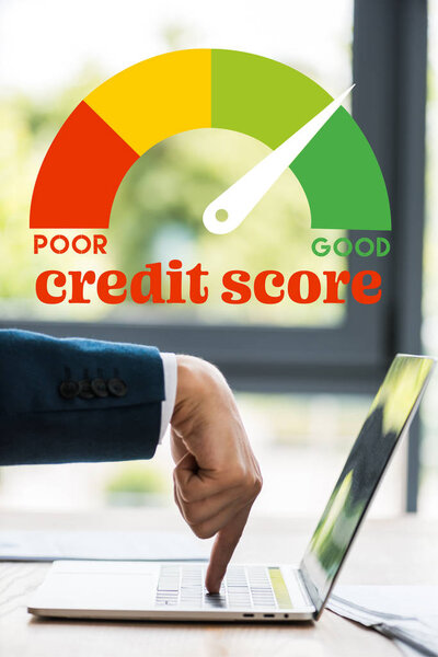 cropped view of businessman pointing with finger at laptop keyboard near credit score letters 