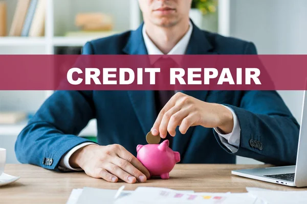 cropped view of businessman putting metallic coin into pink piggy bank near credit repair letters