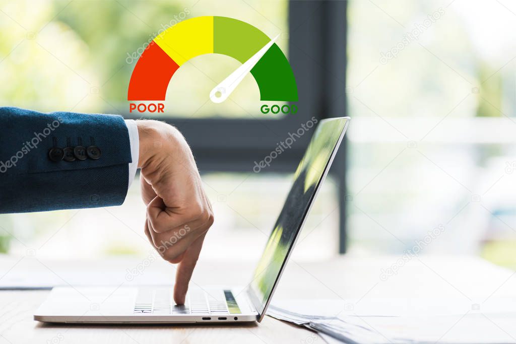 cropped view of businessman pointing with finger at laptop keyboard near speed meters and letters 