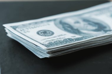 selective focus of stack with dollar banknotes on black  clipart