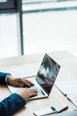 boş ekranile akıllı telefon yakınında dizüstü bilgisayarda yazarak adam kırpılmış görünümü