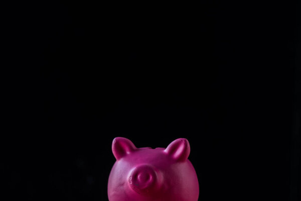 pink toy piggy bank isolated on black with copy space