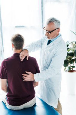 klinikte chiropractor yakınında oturan hastanın arka görünümü 