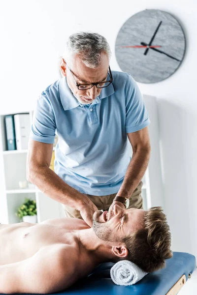 Chiropratico Barbuto Che Massaggio All Uomo Con Dolore Sul Lettino — Foto Stock