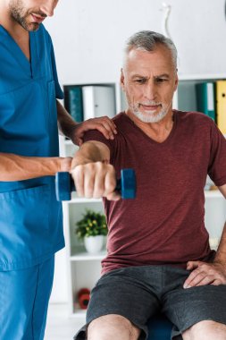 dambıl ile egzersiz orta yaşlı adam yakınında duran sakallı doktor kırpılmış görünümü 