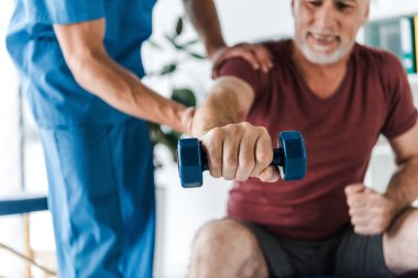 doktor yakınında dumbbell ile çalışan neşeli olgun adam seçici odak 