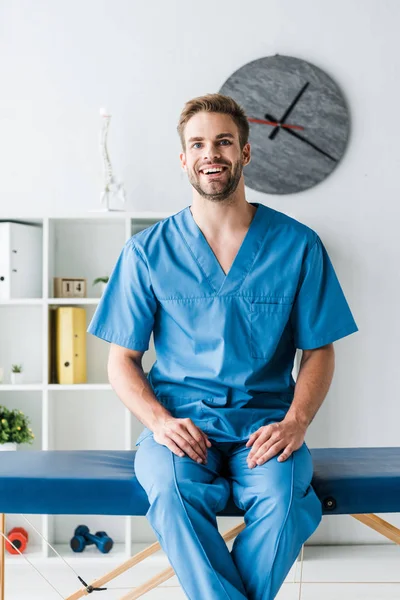 Medico Felice Guardando Fotocamera Mentre Seduto Clinica — Foto Stock