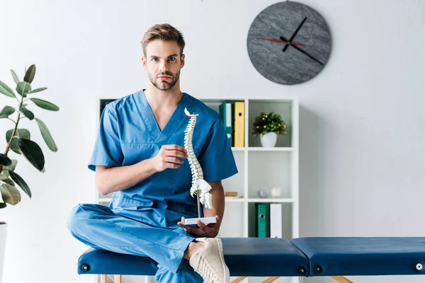 Medico Che Guarda Fotocamera Mentre Tiene Modello Colonna Vertebrale Clinica — Foto Stock