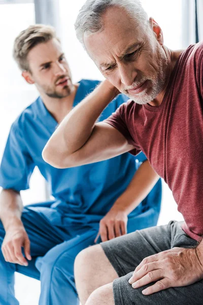 在诊所医生附近疼痛时 男子触摸颈部的选择性焦点 — 图库照片