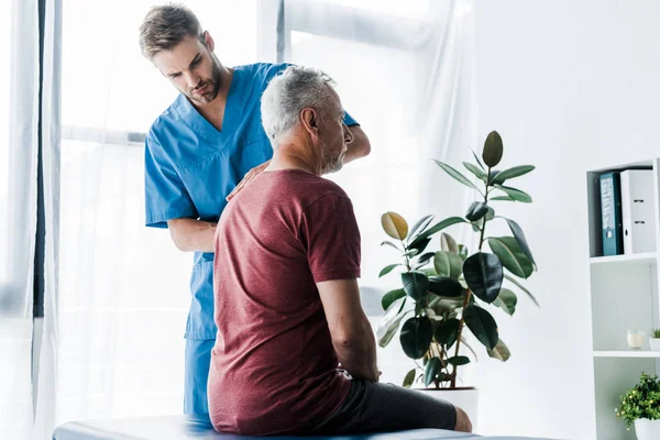 Stilig Kiropraktor Stående Nära Mogen Patient — Stockfoto