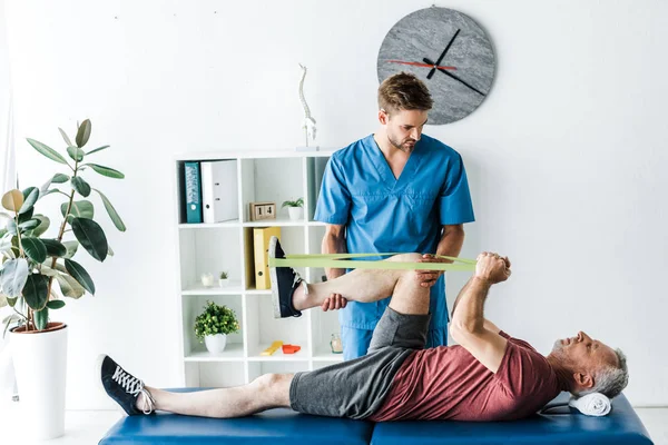 Schöner Arzt Hält Bein Eines Reifen Patienten Der Der Klinik — Stockfoto