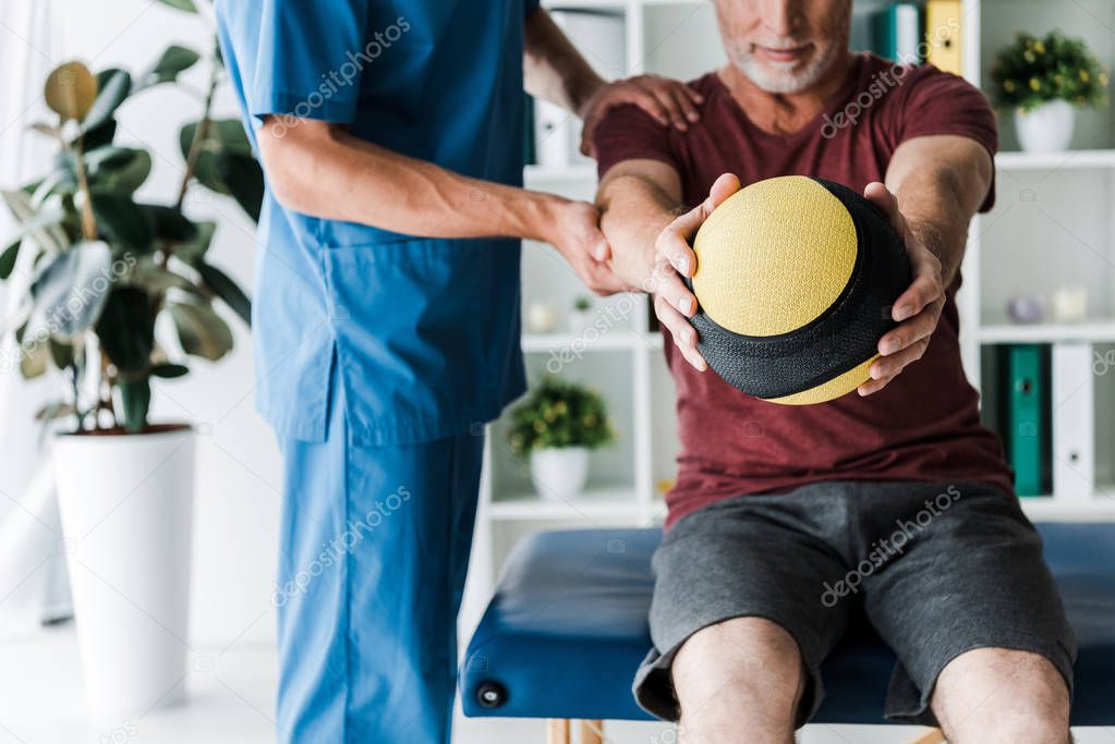 cropped view of mature man training with ball near doctor 