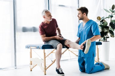 yakışıklı doktor bacak dokunmadan ve olgun hasta bakıyor 