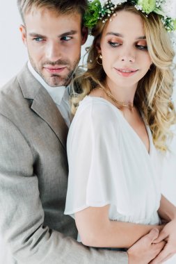 çekici gelin ve yakışıklı damat sarılma ve gri izole uzak bakıyor