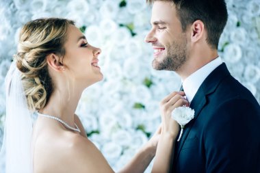 çekici gelin ve yakışıklı damat gülümseyerek ve birbirlerine bakıyor 