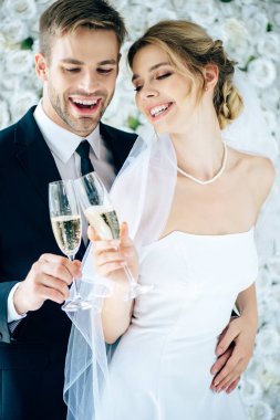 çekici gelin ve yakışıklı damat gülümseyen ve şampanya bardakları ile klinking