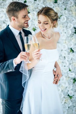 çekici gelin ve yakışıklı damat gülümseyen ve şampanya bardakları ile klinking
