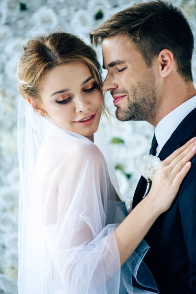 attractive bride and handsome bridegroom hugging with closed eyes 