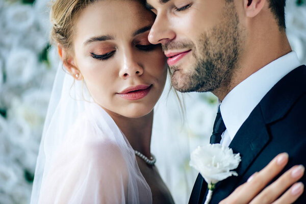 attractive bride and handsome bridegroom hugging with closed eyes 
