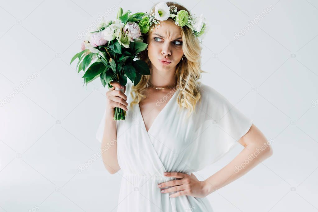 attractive bride in wedding dress and wreath holding bouquet isolated on white