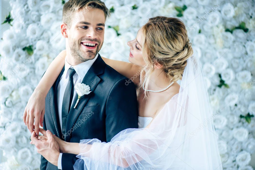 attractive bride and handsome bridegroom smiling and looking at each other 