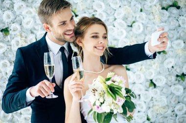 çekici gelin ve yakışıklı damat gülümseyerek ve selfie alarak 