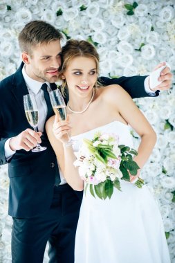 çekici gelin ve yakışıklı damat gülümseyerek ve selfie alarak 