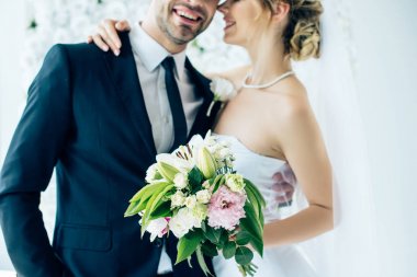 cropped vie of bride in wedding dress and bridegroom hugging each other  clipart