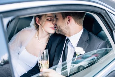 çekici gelin ve yakışıklı damat öpüşme ve şampanya bardakları tutarak