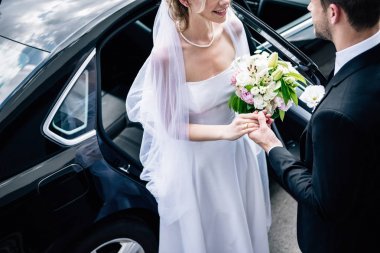 buket ile geline el veren takım elbise damat kırpılmış görünümü