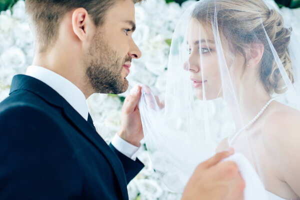 side view of attractive bride and handsome bridegroom looking at each other 